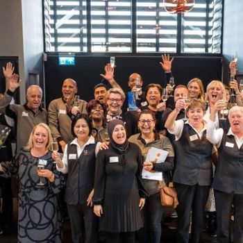 Groepsfoto van collega's van schoonmaakbedrijf die juichen